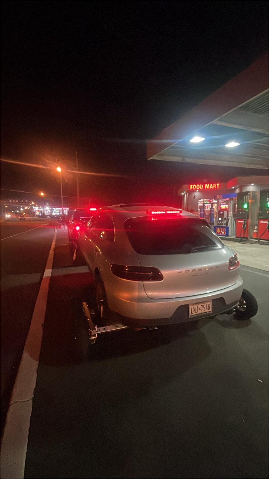 Porsche being towed at night near gas station